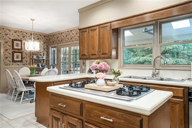 2080 Old Dominion Rd, Atlanta, GA 30350 - kitchen with wallpapered walls, white stovetop, wainscoting, light countertops, and brown cabinetry