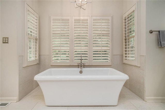 2080 Old Dominion Rd, Atlanta, GA 30350 - full bathroom with a soaking tub, tile patterned floors, tile walls, a wainscoted wall, and a chandelier