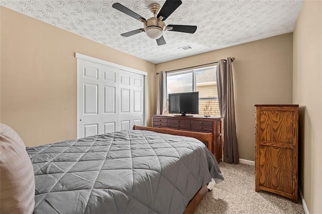 bedroom featuring ceiling fan, light colored carpet, a closet, and a textured ceiling