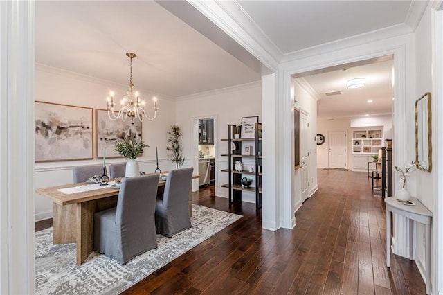 dining room with crown molding, dark wood-type flooring, and a chandelier