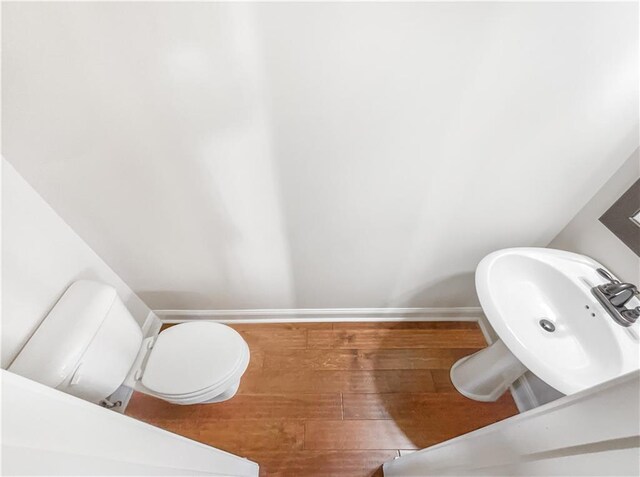 bathroom featuring toilet, wood-type flooring, and sink