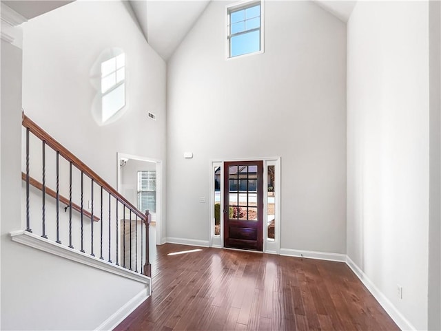 entryway featuring a towering ceiling and dark wood-type flooring