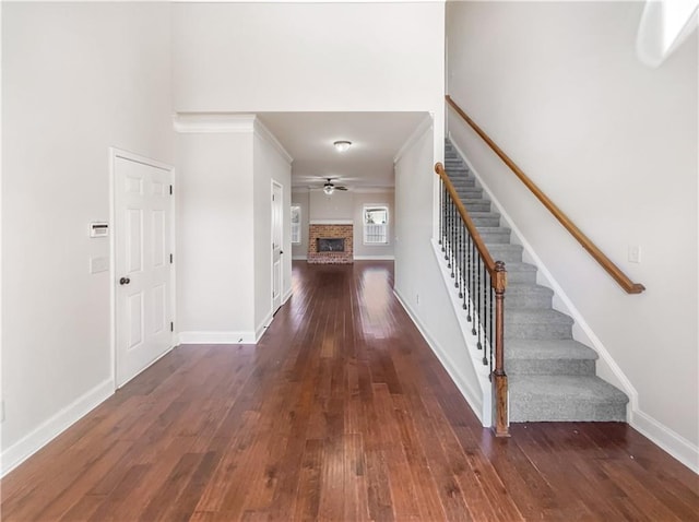 interior space with ceiling fan, dark hardwood / wood-style flooring, crown molding, and a brick fireplace