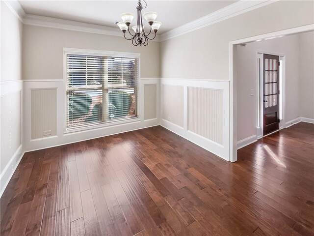 empty room featuring crown molding, dark wood-type flooring, and an inviting chandelier