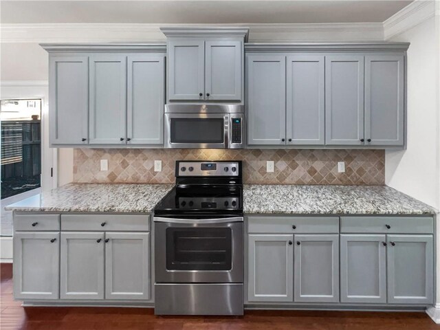 kitchen with tasteful backsplash, light stone counters, crown molding, and appliances with stainless steel finishes