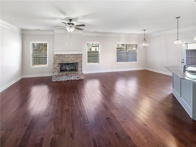 unfurnished living room with ceiling fan, dark hardwood / wood-style flooring, a fireplace, and crown molding