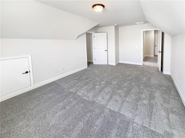 bonus room with dark colored carpet and vaulted ceiling