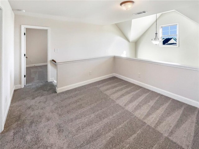 carpeted spare room with lofted ceiling