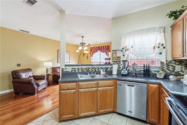 kitchen with sink, kitchen peninsula, ceiling fan, stainless steel appliances, and decorative backsplash