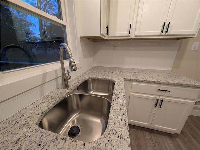 interior details featuring dark hardwood / wood-style flooring, white cabinetry, sink, and light stone counters