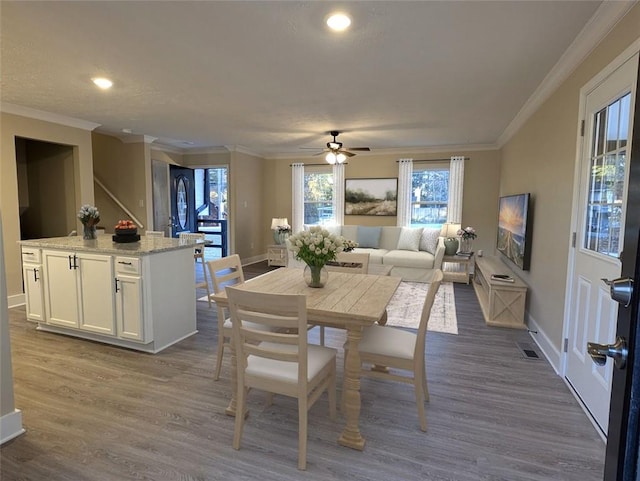 dining space featuring hardwood / wood-style floors, ceiling fan, and crown molding