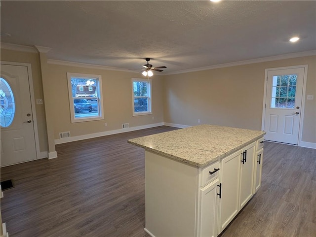 kitchen with crown molding, dark hardwood / wood-style floors, ceiling fan, a kitchen island, and white cabinetry