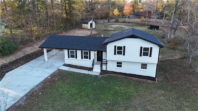 view of front of house featuring a front yard, a carport, and a storage shed