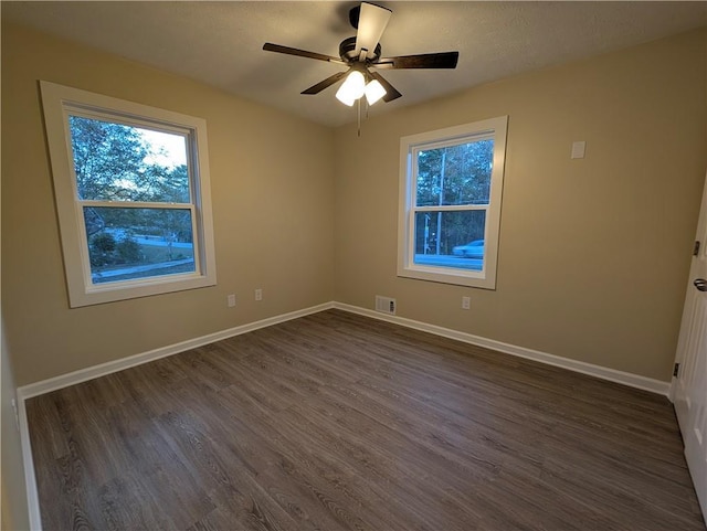 empty room with ceiling fan and dark hardwood / wood-style flooring