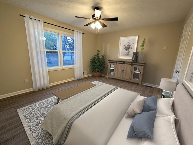 bedroom with a textured ceiling, dark hardwood / wood-style floors, and ceiling fan