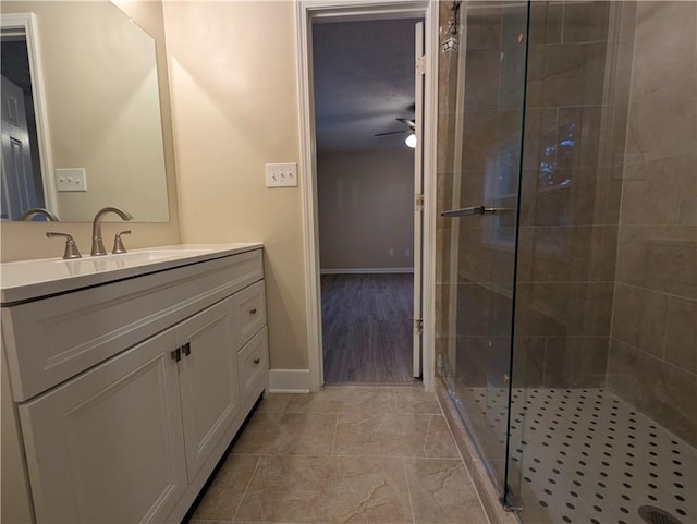 bathroom featuring vanity, hardwood / wood-style flooring, a shower with door, and ceiling fan