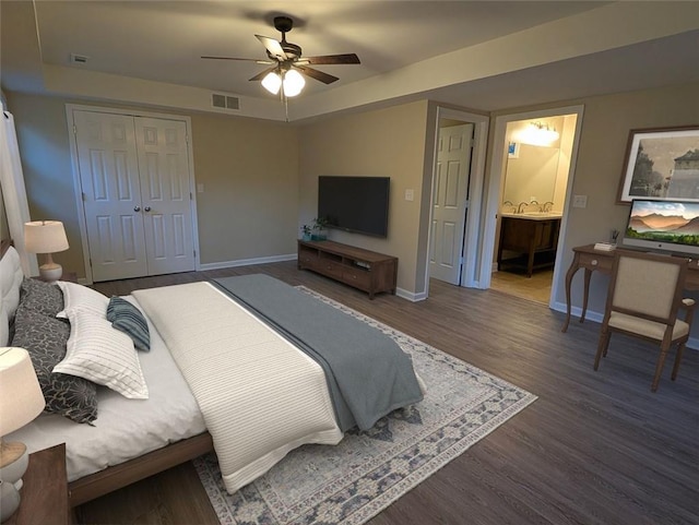 bedroom featuring ceiling fan, dark hardwood / wood-style flooring, ensuite bath, and a closet