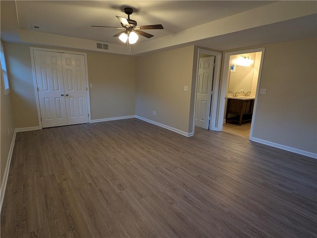 unfurnished bedroom featuring a closet, dark hardwood / wood-style floors, ceiling fan, and connected bathroom