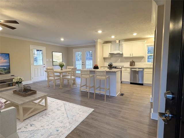 kitchen with white cabinetry, dishwasher, a breakfast bar, a kitchen island, and light wood-type flooring