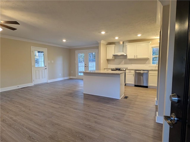 kitchen featuring white cabinets, light wood-type flooring, stainless steel appliances, and wall chimney range hood