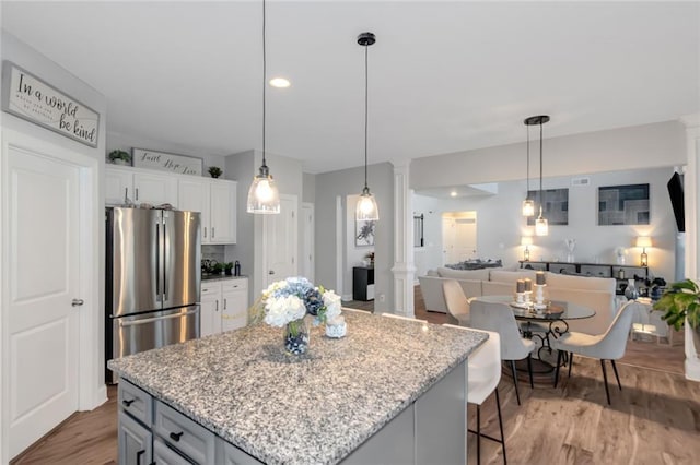 kitchen with decorative columns, light wood-style floors, freestanding refrigerator, open floor plan, and white cabinets