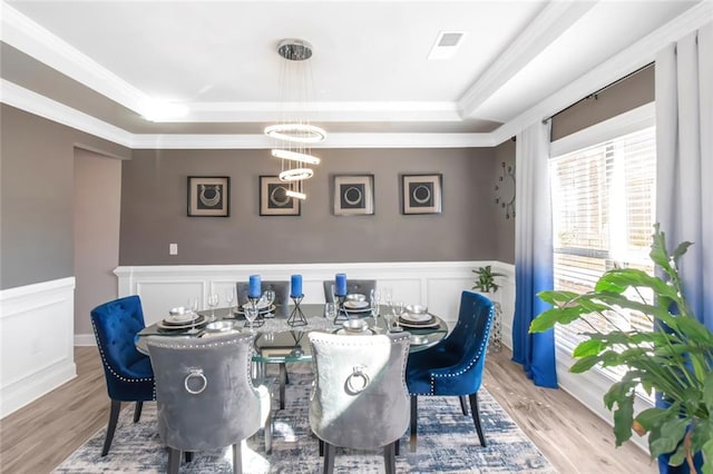 dining area featuring a wainscoted wall, a raised ceiling, and wood finished floors