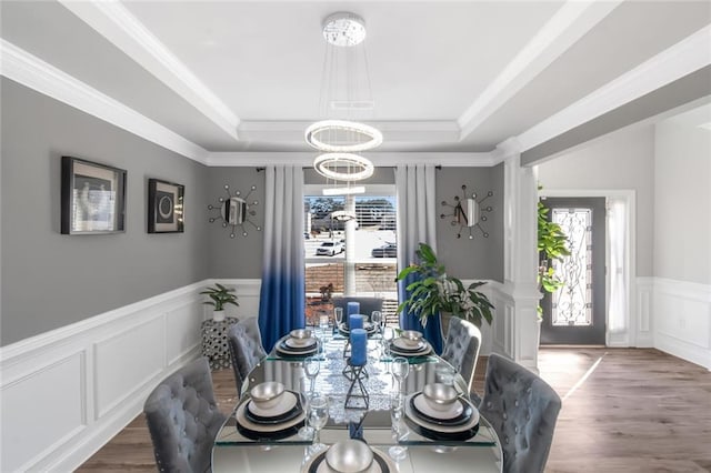 dining space with wood finished floors, a raised ceiling, and a wealth of natural light