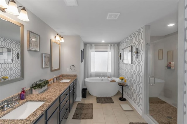 bathroom featuring a stall shower, a freestanding tub, a sink, and double vanity