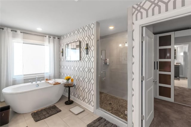 bathroom featuring a stall shower, tile patterned flooring, a freestanding tub, and wallpapered walls