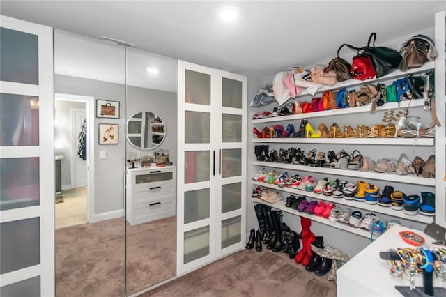 walk in closet with visible vents and light colored carpet