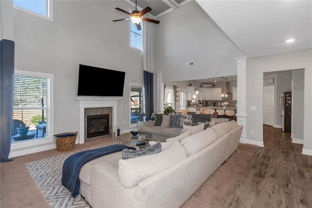 living area with a fireplace, decorative columns, visible vents, ceiling fan, and baseboards