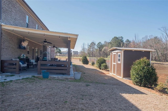 view of yard featuring an outbuilding, ceiling fan, fence, and a shed