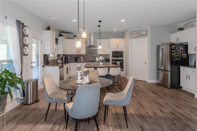 dining space featuring baseboards, wood finished floors, and recessed lighting