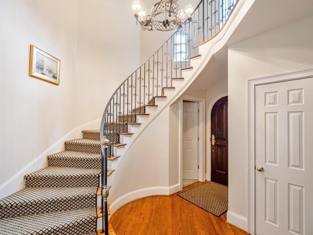 staircase featuring a notable chandelier, a high ceiling, and hardwood / wood-style flooring