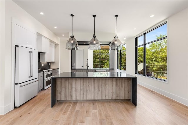 kitchen with built in refrigerator, range with two ovens, a kitchen island, white cabinets, and sink