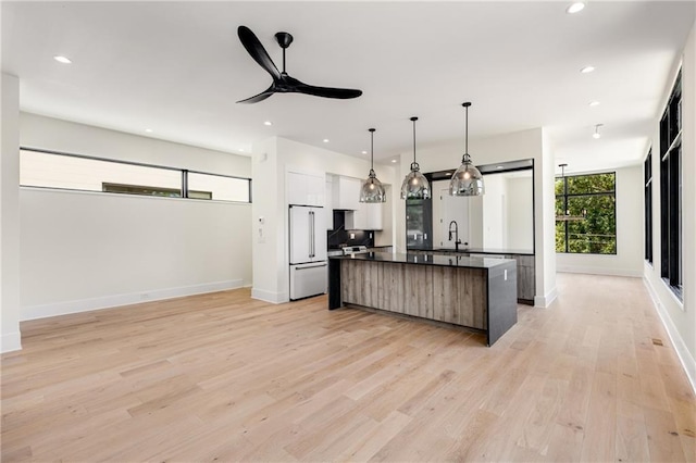 kitchen featuring built in fridge, decorative light fixtures, white cabinetry, a center island, and light hardwood / wood-style flooring