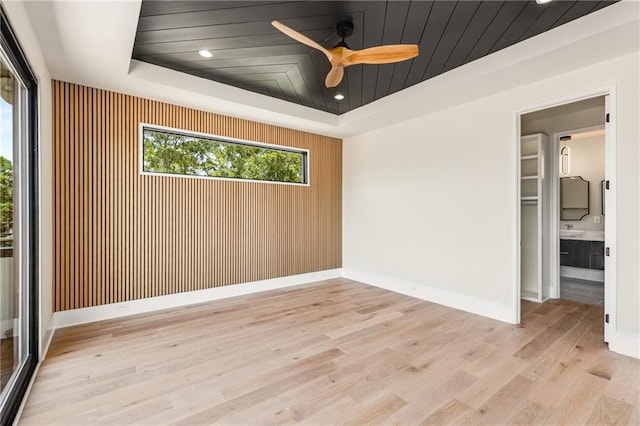 empty room featuring a raised ceiling, ceiling fan, and light hardwood / wood-style floors