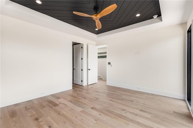 unfurnished room with light hardwood / wood-style floors, wooden ceiling, ceiling fan, and a tray ceiling