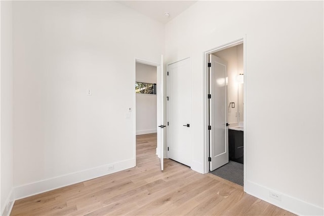 unfurnished bedroom with ensuite bathroom and light wood-type flooring