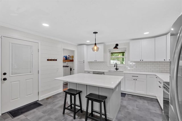 1162 Newtown Church Rd NE, Calhoun, GA 30701 - kitchen featuring appliances with stainless steel finishes, ornamental molding, a kitchen breakfast bar, washer and clothes dryer, and white cabinets