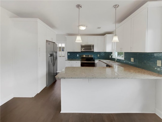 kitchen with appliances with stainless steel finishes, hanging light fixtures, white cabinets, kitchen peninsula, and dark hardwood / wood-style floors