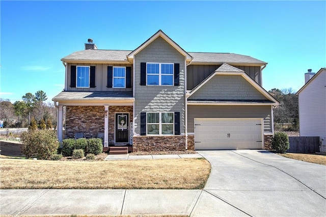 view of front of house featuring a garage, driveway, stone siding, fence, and board and batten siding