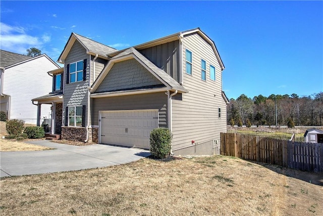 view of side of property with a garage, fence, and concrete driveway