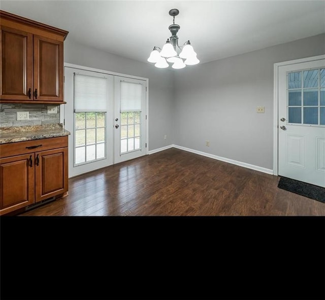 unfurnished dining area with dark hardwood / wood-style floors, a notable chandelier, and french doors