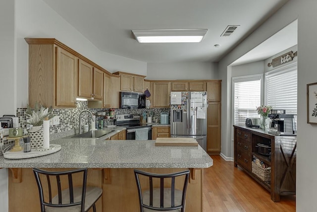 kitchen featuring stainless steel appliances, visible vents, decorative backsplash, a sink, and a peninsula