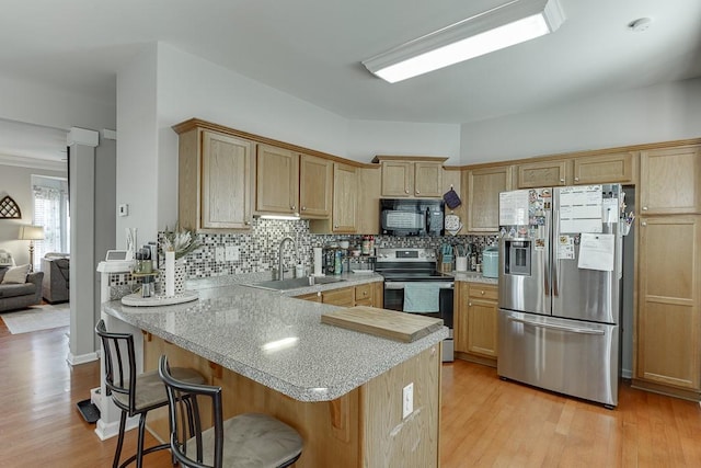 kitchen featuring a peninsula, stainless steel appliances, a sink, and light countertops