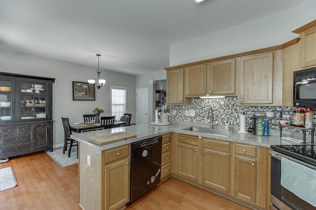 kitchen with light wood-style flooring, a peninsula, a sink, backsplash, and black appliances