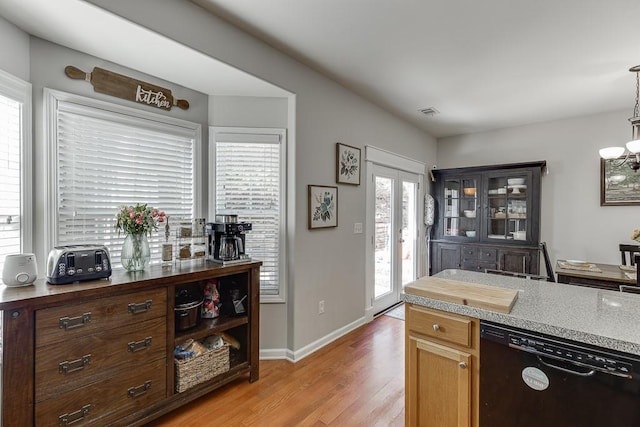 kitchen featuring a notable chandelier, light wood-style floors, light countertops, dishwasher, and pendant lighting