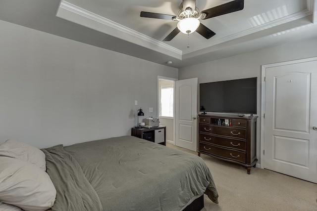 bedroom with ornamental molding, a tray ceiling, a ceiling fan, and light colored carpet