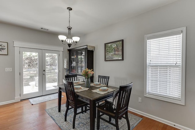 dining space with french doors, visible vents, an inviting chandelier, wood finished floors, and baseboards